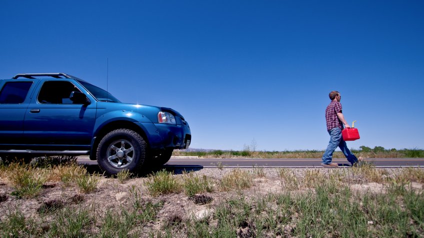 Young man filling empty gas tank in his pickup with a gas can.