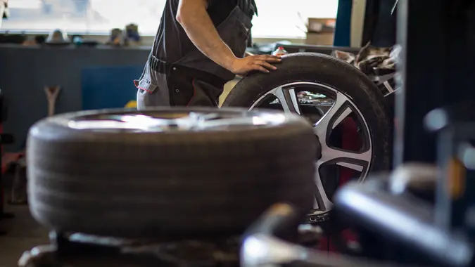 Wheel balancing or repair and change car tire at auto service garage or workshop by mechanic.