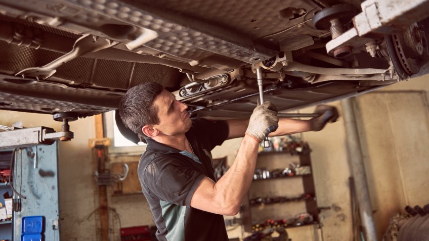 Close up view of car mechanic making effort for screwing up auto detail.