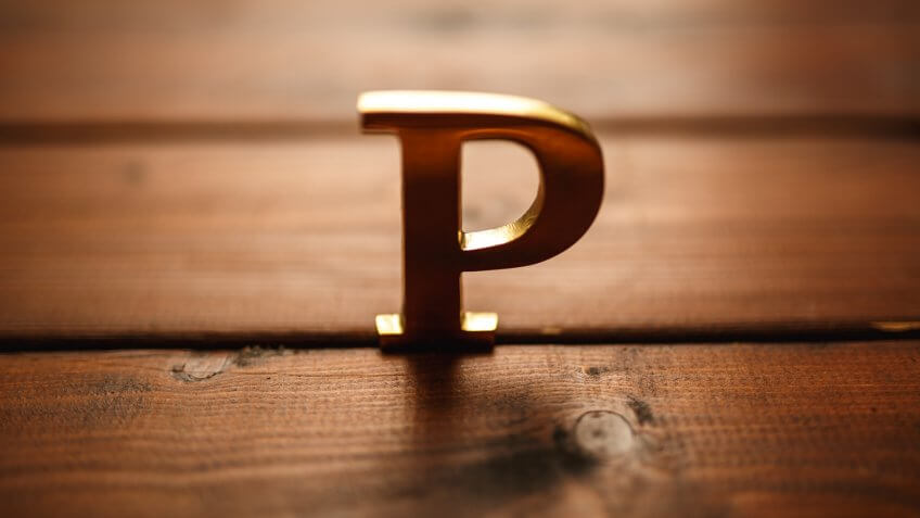 Gold metal letter P on wood selective focus.