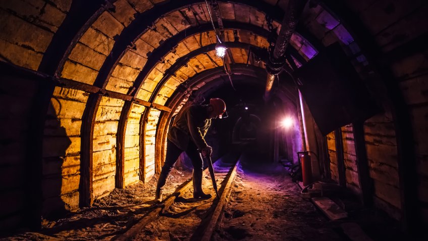 Miner working a jackhammer in a coal mine.