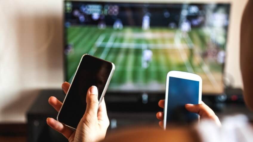 Friends using mobile phone during a tennis match on the TV.