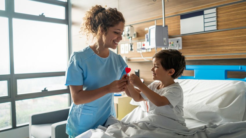 Young beautiful nurse giving a lollipop to pediatrics hospitalized patient smiling very happy.