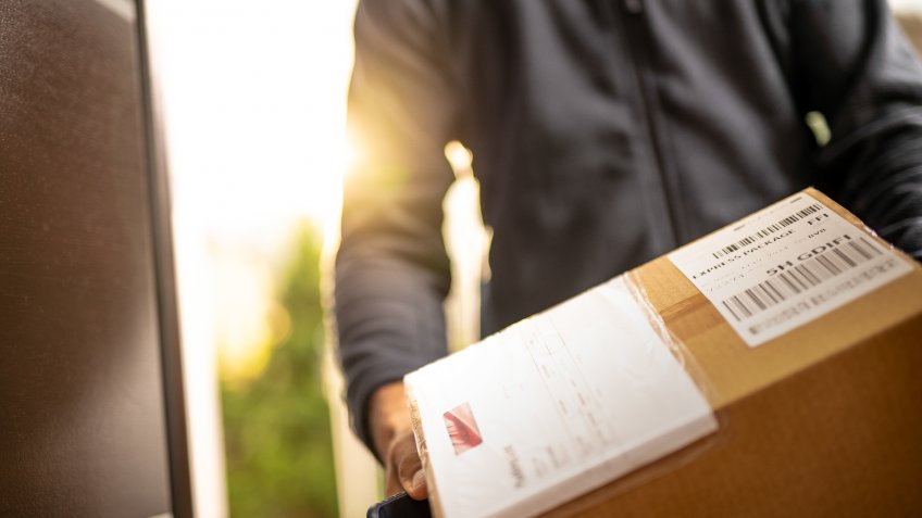 Close up of an unrecognisable courier holding cardboard box prepared for home delivery.