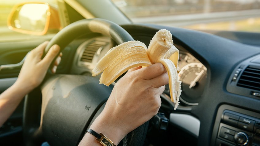 person eating banana snack in car