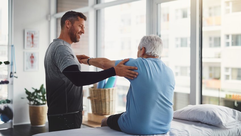 Shot of a young male physiotherapist assisting a senior patient in recovery.