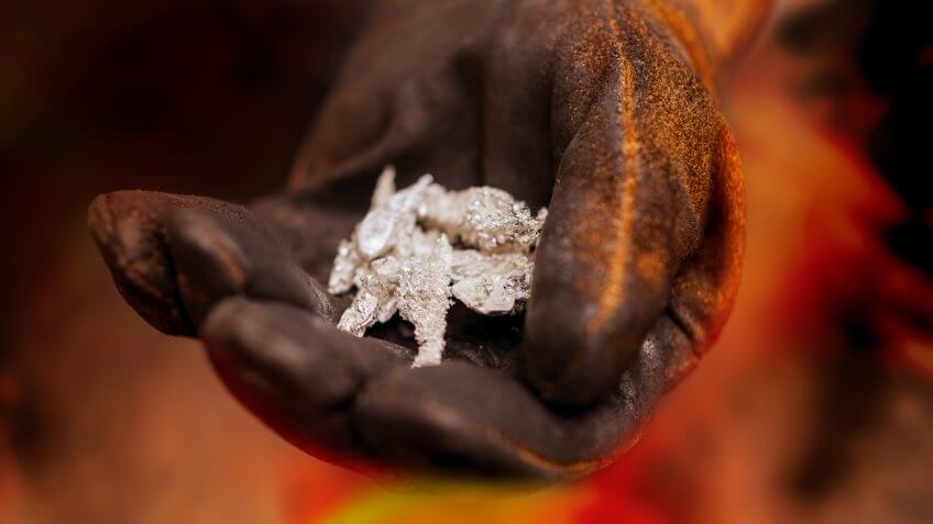 Pure silver crystals with glove in industrial setting.
