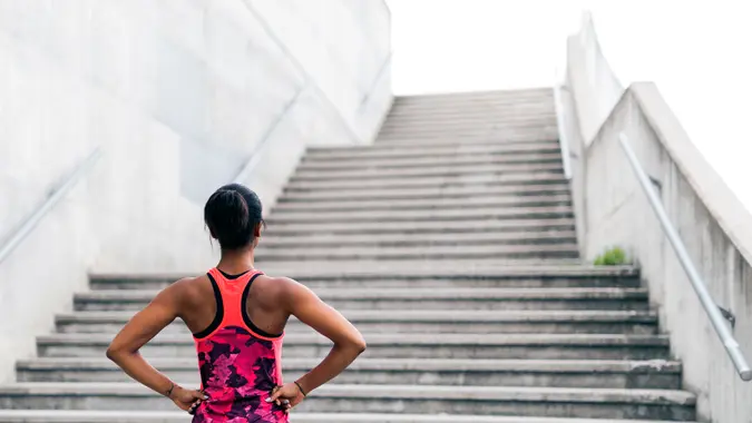 Young woman standing in front of a set of stairs, preparation and determination.