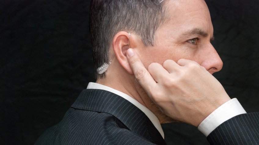 Close-up of a secret service agent listening to his earpiece, side.