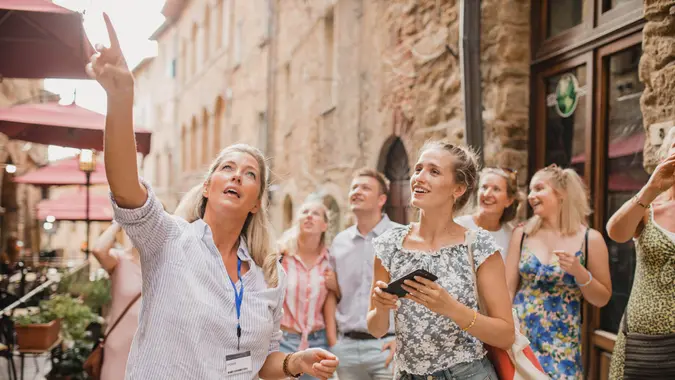 A group of people listen as a tour guide shows them the city.