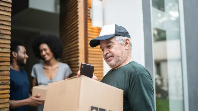 Courier delivering boxes to a young couple.