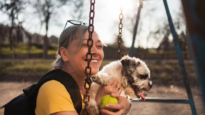 Close up of Senior woman sitting on swing with dog.