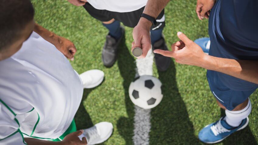 cropped shot of referee holding coin before start of soccer match on pitch.