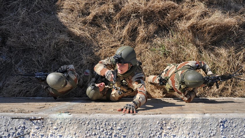 Four soldiers are climbing a wall and they are ready to fight.