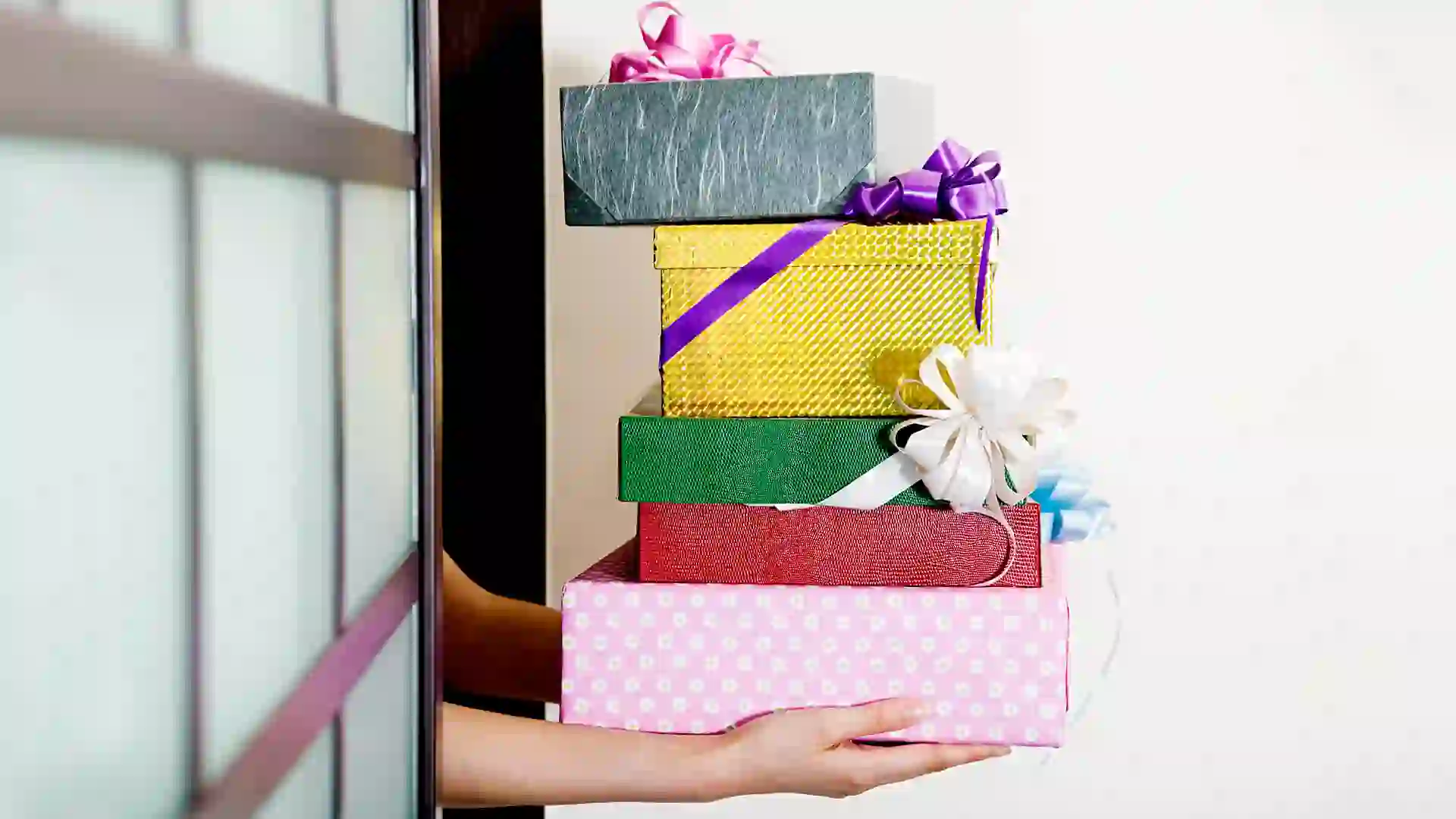 birthday, box, doorway, enter, female, generosity, gift, holding, human arm, indoors, one person, only one young adult woman, ribbon, stack, woman, young adult, young woman, horizontal, color, photography