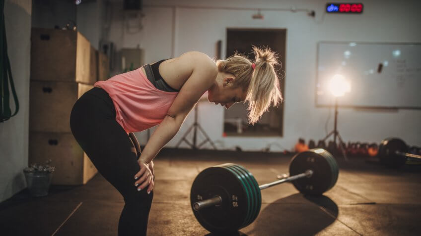 One woman in gym, girl tired of weights training.
