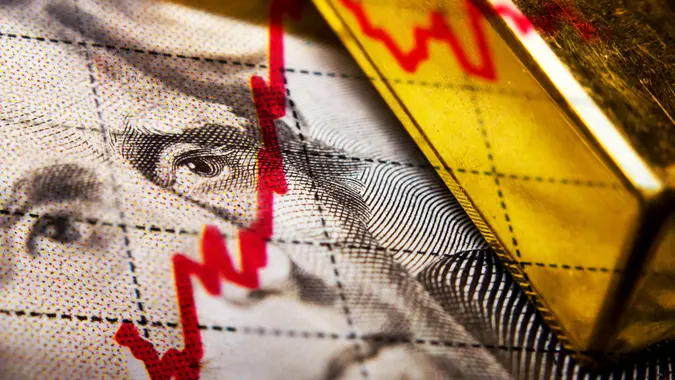 Close up of a dollar banknote and gold ingot and a financial chart.