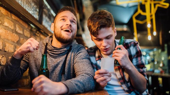 Young men watching a game on TV and drinking beer at the pub.