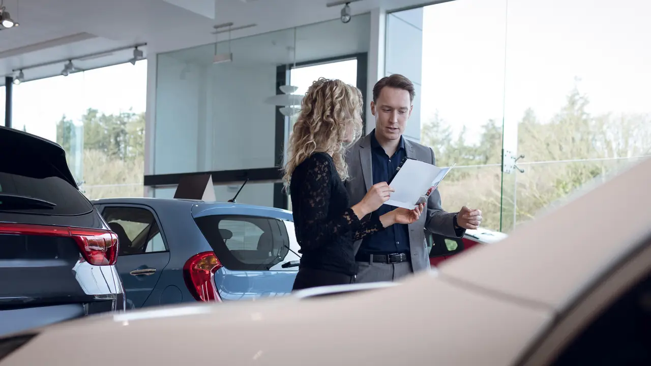 woman asking male car dealer about loan terms