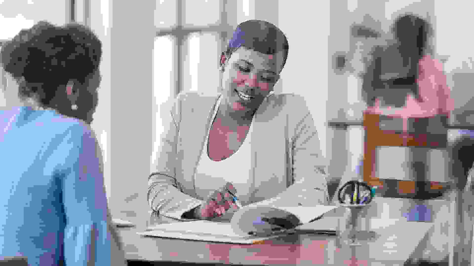 Mid adult African American female loan officer reviews loan terms with a female customer.