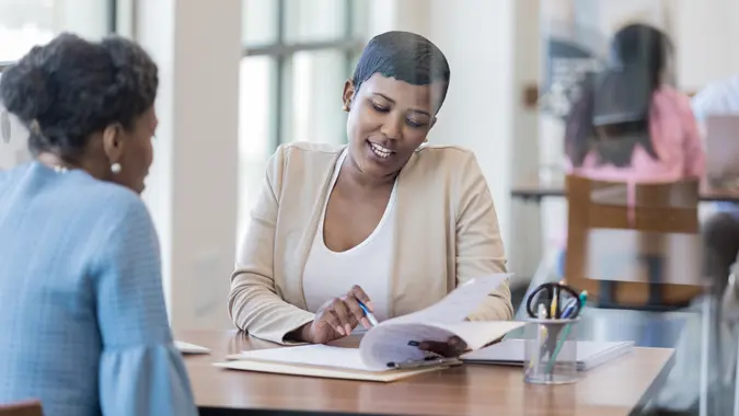 Mid adult African American female loan officer reviews loan terms with a female customer.