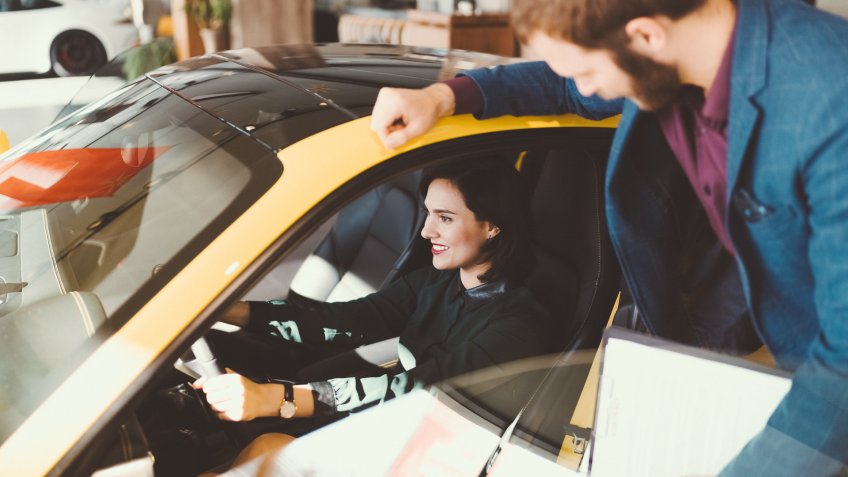 Smiling woman in the showroom enjoying a car.