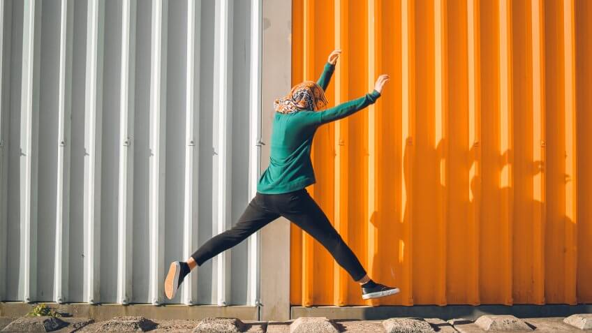 Young Muslim woman wearing scarf and jumping.