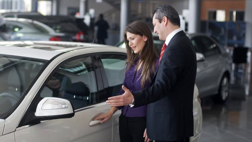 Female with car salesperson and she thinks about buying the car.