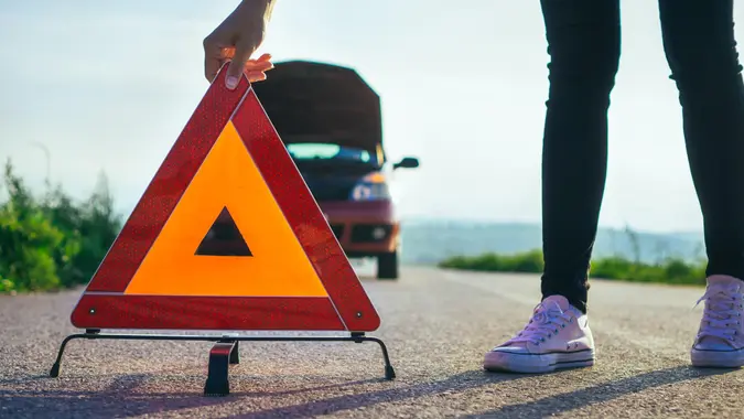 Woman have car breakdown in a rural landscape.
