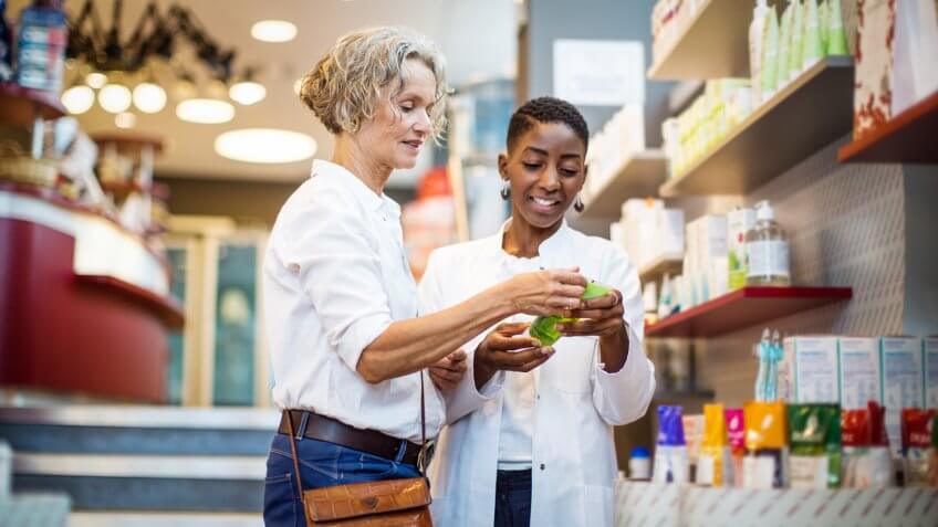 Female pharmacist assisting senior customer in the store.