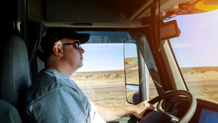 Closeup of driver's hands on big truck steering wheel.