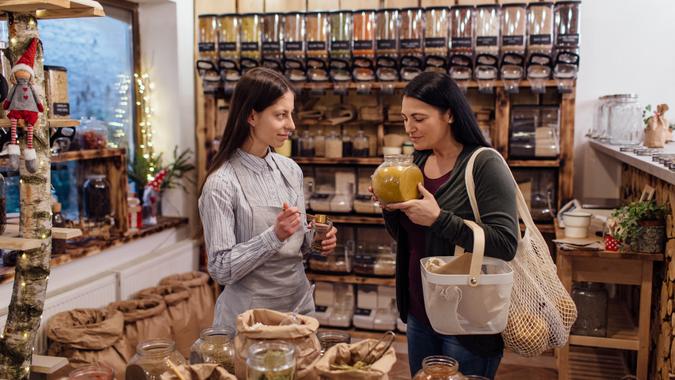 Cheerful shop assistant helping customer in packaging free shop.