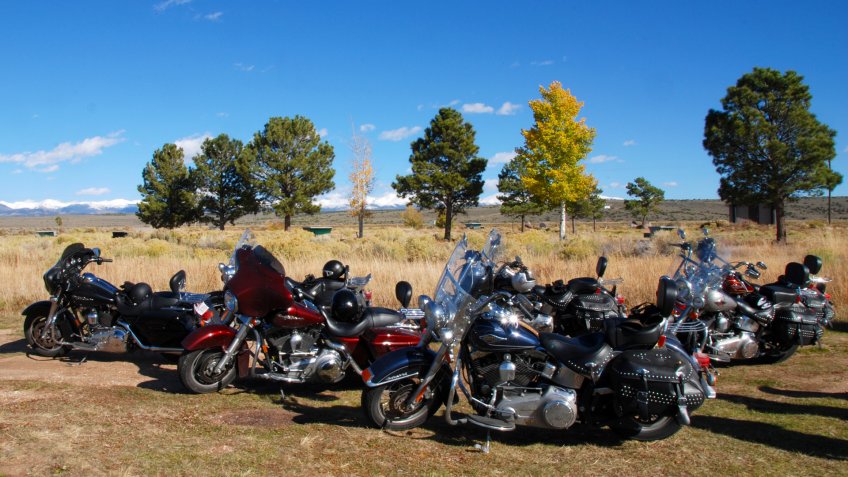 Garcia, Colorado, 10/09/2009 American motorcycles parking in plain field with fall colored trees and snow covered mountains in the background - Image.