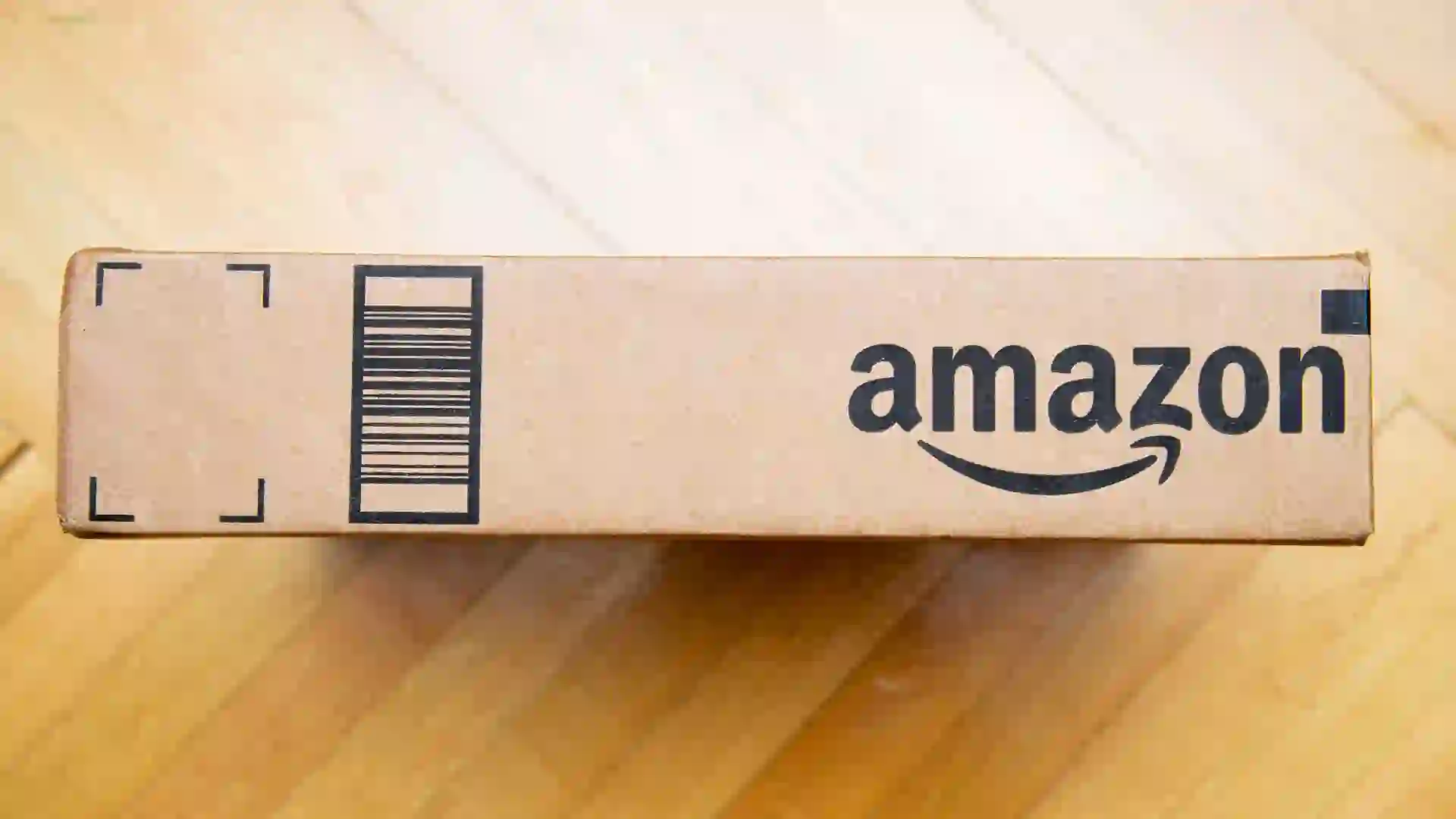 PARIS, FRANCE - JAN 28, 2016: Amazon logotype printed on cardboard box side seen from above on a wooden floor Amazon is the an American electronic e-commerce company - Image.