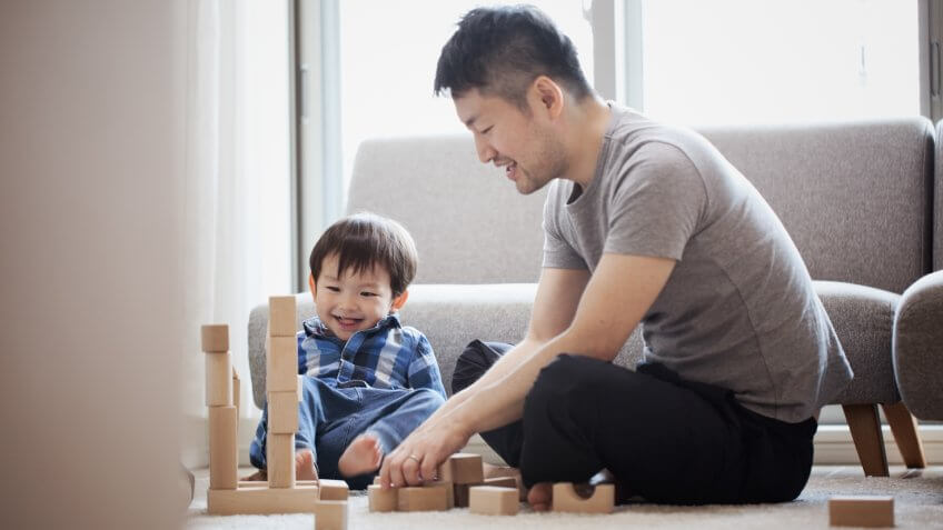 Asian father and son playing a brick sitting on floor.