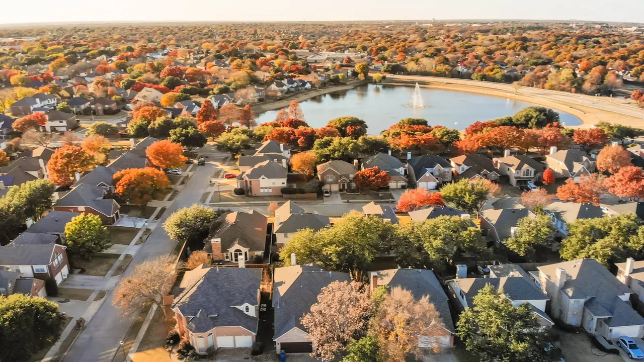 Aerial view lakeside houses neighborhood with colorful autumn leaves.