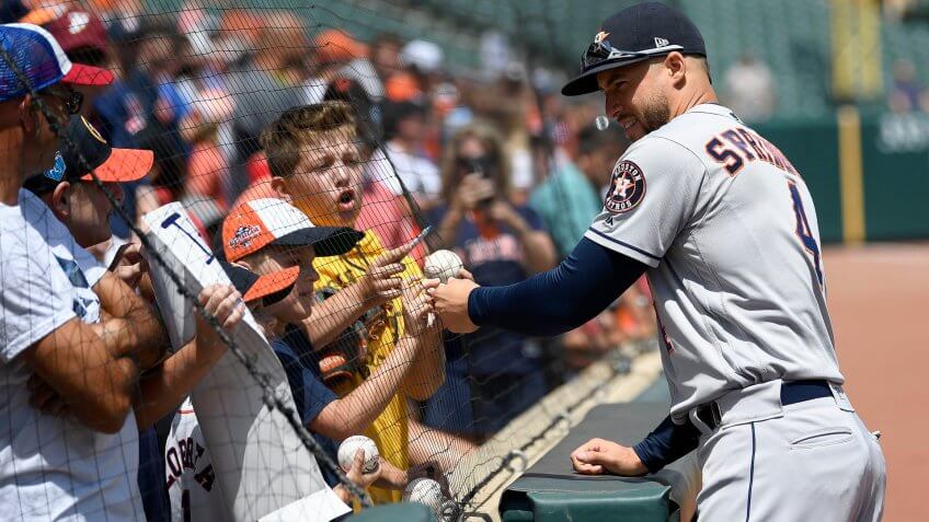 Houston Astros baseball player signs balls during day game