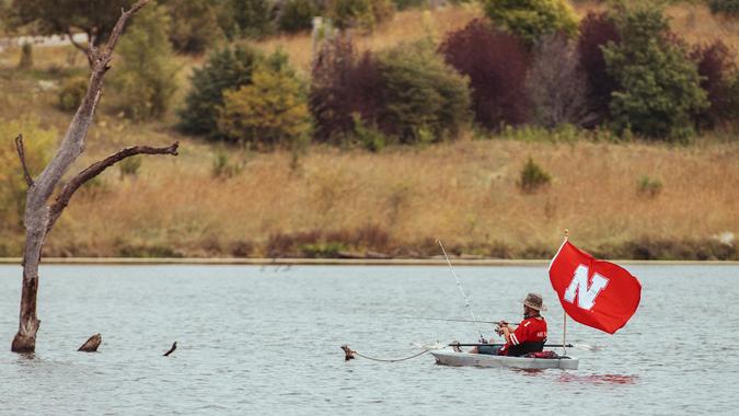 Papillion, NE / USA - October 5, 2019: University of Nebraska Husker college football fan fishing with large Husker flag and Husker jersey.