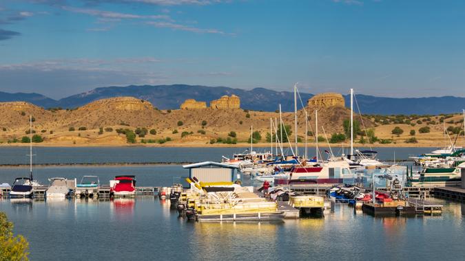 PUEBLO, CO, USA-16 JULY 18: Colorful boats in foreground, rock formations in midground, a distant mountan range, and wispy clouds above--Pueblo State Park.