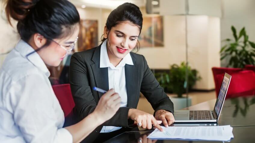 Indian female agent helping client sign the application document.