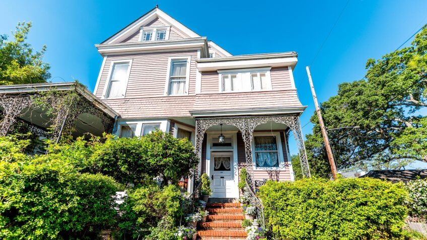 New Orleans, USA - April 23, 2018: Old street historic Garden district in Louisiana famous town city with real estate historic white house blue sky.