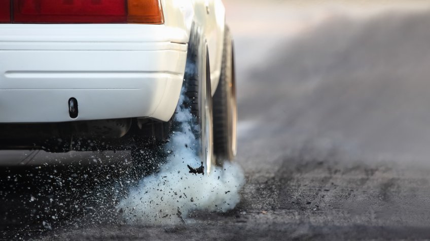 Drag racing car burns rubber off its tires in preparation for the race.