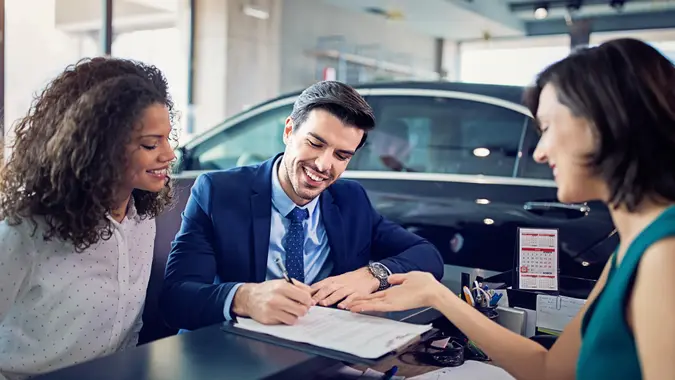 Couple is buying/lease new car and signing the contract.