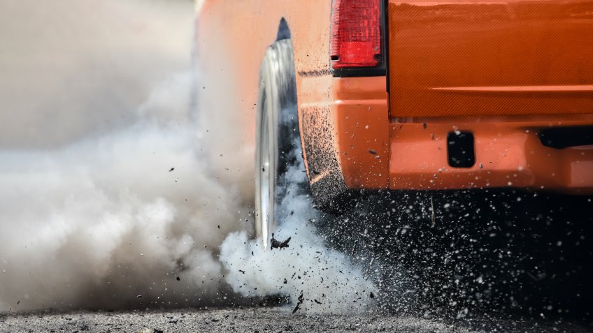 Drag racing car burns rubber off its tires in preparation for the race.