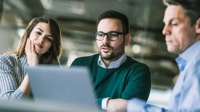 Young couple using computer with their insurance agent on a meeting in the office.