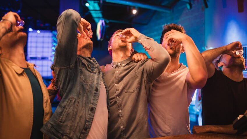 Group of male friends taking shots together on their night out.