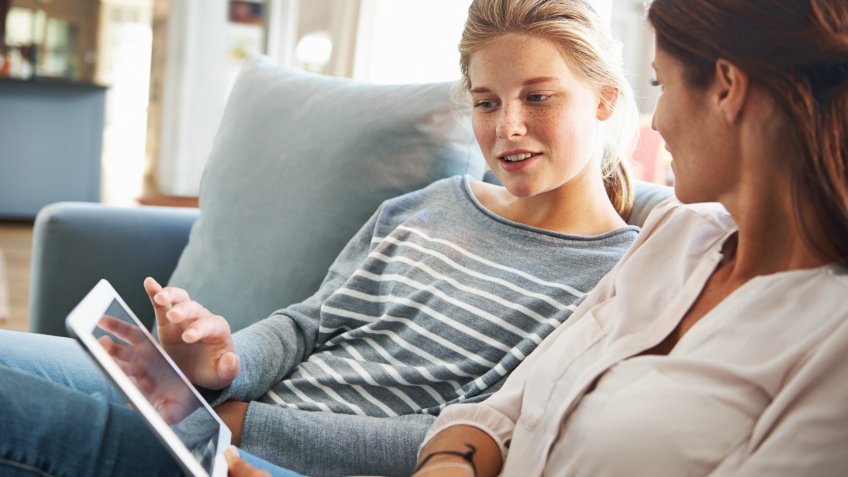 A mom and her teenage daughter spending some quality time together in the living room.
