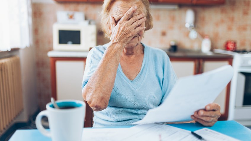 Elderly woman looking at her utility bills and paperwork.