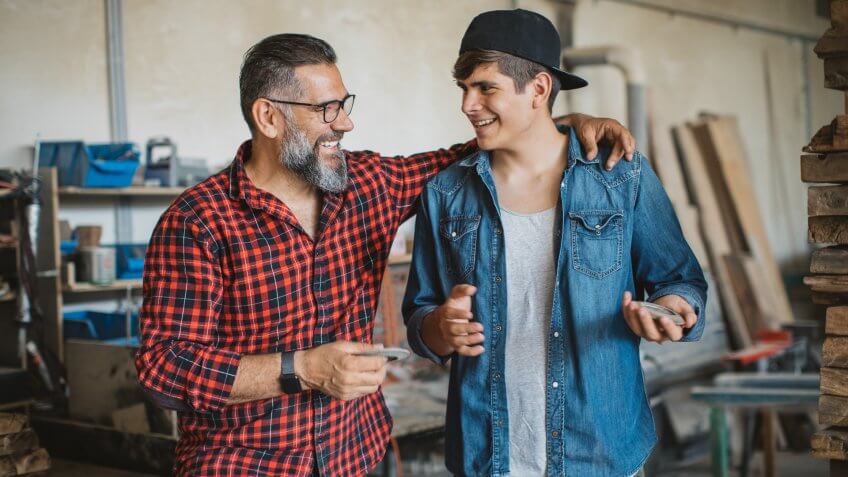 Father and son in carpenter workshop.