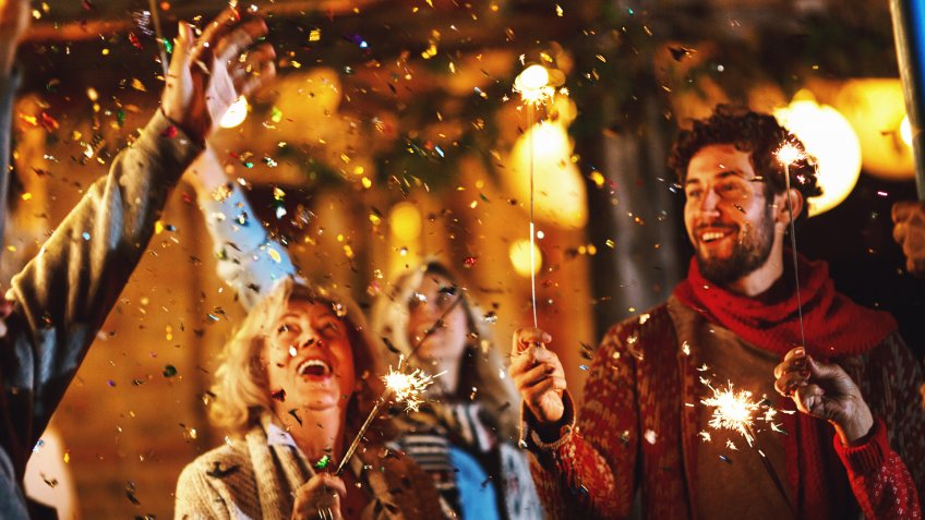Family dancing and celebrating New Year's Eve outdoors.